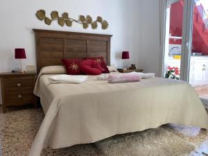 une chambre avec un grand lit avec des oreillers rouges dans l'établissement La casa amarilla de Luis y Eileen, à La Vila Joiosa