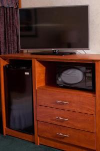 uma televisão num centro de entretenimento em madeira com um micro-ondas em Anchorage Inn Burlington em Burlington