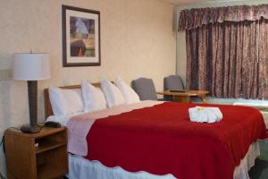 a hotel room with a bed with a red blanket at Anchorage Inn Burlington in Burlington