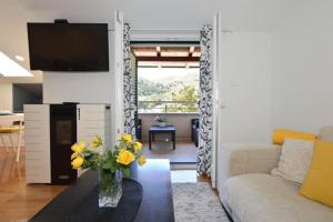 a living room with a vase of yellow flowers on a table at Apartment Leo in Ploče