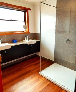 a bathroom with two sinks and a glass shower at Percy's Cottage in Devonport +8 photos