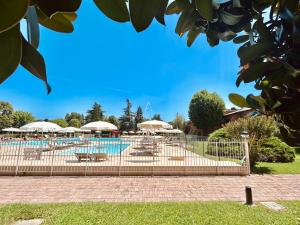 una piscina con tavoli, sedie e ombrelloni di Flora Apt -100m dal Lago di Garda - Piscina a Sirmione