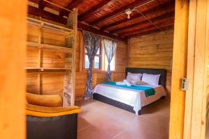a bedroom with a bed in a wooden cabin at Cabaña la Divisa in Jardin