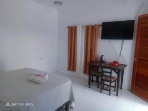 a room with a table and a television and a desk at Jupiters Garden Cottages in Lawa-an