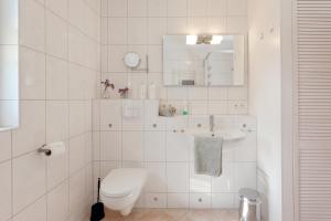 a white bathroom with a toilet and a sink at Haus 113, Birkenweg 6 a in Ostseebad Karlshagen +12 photos