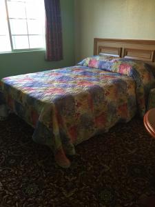 洛杉磯的住宿－樂斯酒店，卧室内一张带五颜六色棉被的床