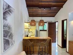 a kitchen with a bar with two stools at Oka Káa - Bosque da Praia Pipa Flat 33 in Pipa