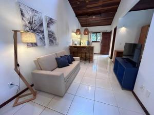 a living room with a couch and a television at Oka Káa - Bosque da Praia Pipa Flat 33 in Pipa