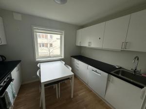 Una cocina con gabinetes blancos y un fregadero y una ventana. en City Apartments - Stavanger, en Stavanger