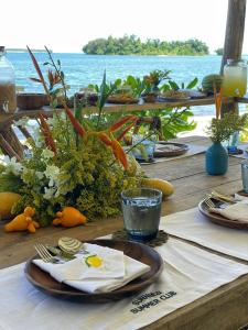 a wooden table with plates and utensils on top of the ocean at INARA Siargao in General Luna