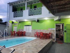 ein Haus mit einem Pool und roten Stühlen in der Unterkunft Unidades 1 e 2 e 3 Pousada do Sossego Mar e Verde in Itanhaém