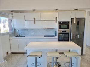 une cuisine avec des armoires blanches et un comptoir avec des tabourets dans l'établissement Departamento Pinterest Mar del Plata - Vista plena al mar con cochera, à Mar del Plata