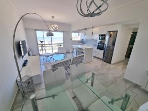 Il dispose d'une cuisine et d'un salon avec une table et des chaises en verre. dans l'établissement Departamento Pinterest Mar del Plata - Vista plena al mar con cochera, à Mar del Plata