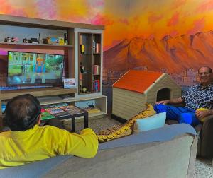 two men sitting in a living room playing a video game at Tajmani Hostel Arequipa in Arequipa