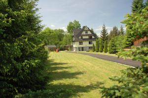 a house with a large lawn in front of a road at Apartamenty Cicha Dolina in Jurgów