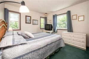 a bedroom with a bed and a tv and windows at 5-Bedroom Lakefront, private beach wifi AC boat & in Tobyhanna