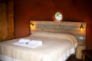 a bedroom with a white bed with a wooden headboard at Willkay Glamping in Tafí Viejo