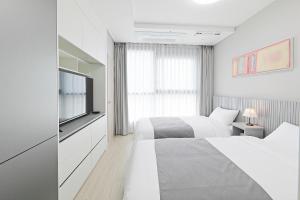 a white bedroom with two beds and a tv at Elmomento Sasang in Busan +95 photos