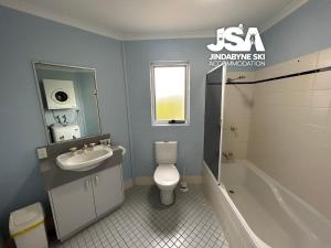 a bathroom with a sink and a toilet and a tub at Parkwood 4 in Jindabyne