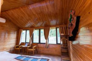 a bedroom in a wooden cabin with a table and chairs at Bac Ha Lodge Retreat in Bắc Hà