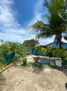 a garden with palm trees and a blue fence at Casa perto da lagoa - Balneário São Pedro in São Pedro da Aldeia