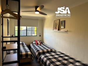 a room with two beds and a ceiling fan at Lakeside Chalet in Jindabyne