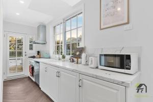 a white kitchen with white cabinets and a microwave at The French Country Cabin in Gordon in Gordon