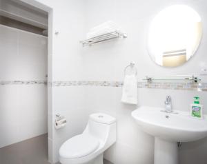 a white bathroom with a toilet and a sink at Airport Costa Rica B&B in Alajuela