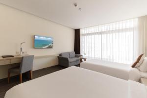 Camera bianca con letto, scrivania, letto e finestra. di Stella Maris Nha Trang Hotel a Nha Trang