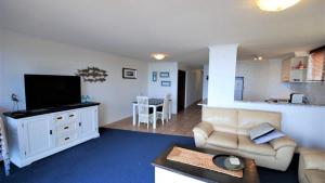 a living room with a couch and a tv and a kitchen at Esplanade View Unit 3 Wollombi in Caloundra
