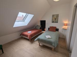 ChaingyにあるGîte 1 Les Ratys : charme, calme et confort près d'Orléans - FR-1-590-523のベッド2台と窓が備わる屋根裏部屋です。