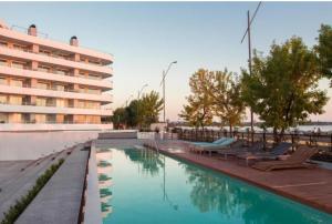 a swimming pool with lounge chairs next to a building at Mono ambiente frente al río, con amenities in Colonia del Sacramento