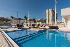 einen Pool mit Stühlen und Tischen sowie ein Gebäude in der Unterkunft Apto Home Club 500m Praia Piçarras 20 min Beto Carrero - ANG905C in Piçarras