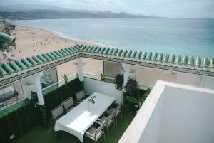 un balcon avec une table et des chaises et une plage dans l'établissement Luxury Beachfront Penthouse with Stunning Views, à Las Palmas de Gran Canaria