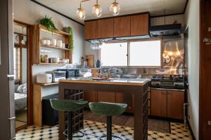 uma cozinha com um balcão e dois bancos de bar em NIKI HOUSE -Yoichi 貸切一軒家 em Kurokawamachi
