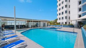 a swimming pool with lounge chairs and a building at Centrepoint Unit 27 in Caloundra