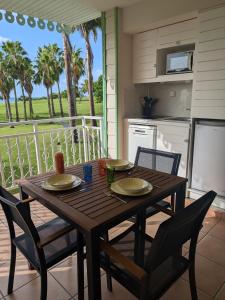 une table en bois avec deux chaises et une cuisine dans l'établissement Ti'Karaïb Appartement Vue Mer, à Sainte-Luce 18 autres photos