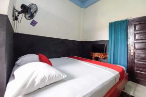 a bedroom with a bed with a fan on the wall at RedDoorz Syariah at Penginapan Queen Sungai Penuh in Sungaitutung