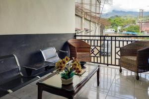 a balcony with chairs and a table with flowers on it at RedDoorz Syariah at Penginapan Queen Sungai Penuh in Sungaitutung