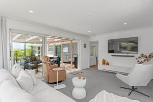 a living room with a white couch and chairs at Tuis and Pools - Lake Taupo Holiday Home in Taupo