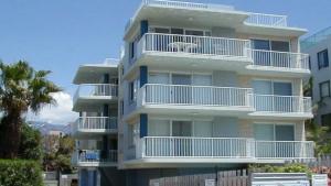 a tall building with white balconies and a palm tree at Spinnaker Seas Unit 2 in Caloundra
