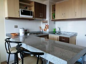 a kitchen with a counter and two stools in it at Departamento completo, centrico y estacionamiento in Temuco +19 photos