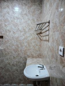 a bathroom with a sink and a tiled wall at Sulfat Indah home stay syariah in Ngadipuro