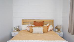 a bed with orange and white pillows on it at Blue Beach House in Caloundra