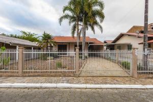 a fence in front of a house with a palm tree at 5 Pessoas | Praia Armação | Beto Carrero in São Lídio