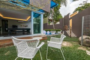 two white chairs and a table in a yard at 6BR Homestay KL Pool Villa - 4KM To KLCC by Verano in Ampang