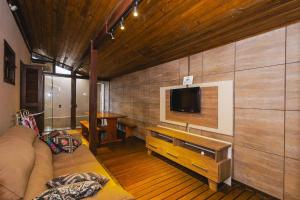 a living room with a couch and a tv on a wall at 5 Pessoas | Praia Armação | Beto Carrero in São Lídio