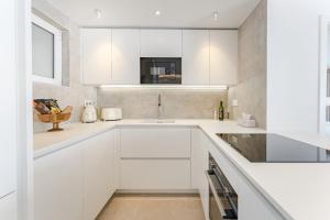 a kitchen with white cabinets and a sink at Blue Haven - Ocean View Penthouse with private jacuzzi and community pool in Acantilado de los Gigantes +36 photos