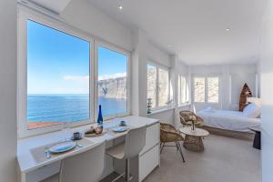 a white bedroom with a bed and a large window at Blue Haven - Ocean View Penthouse with private jacuzzi and community pool in Acantilado de los Gigantes