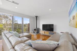 a living room with a couch and a flat screen tv at Banksia Beach Retreat in Blairgowrie